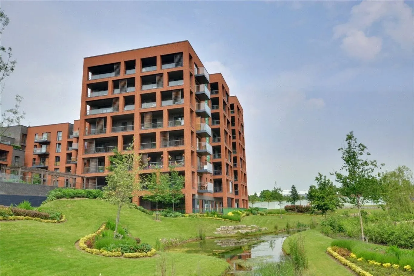 The red-brick Halton Court apartment block above landscaped lawns and a stream